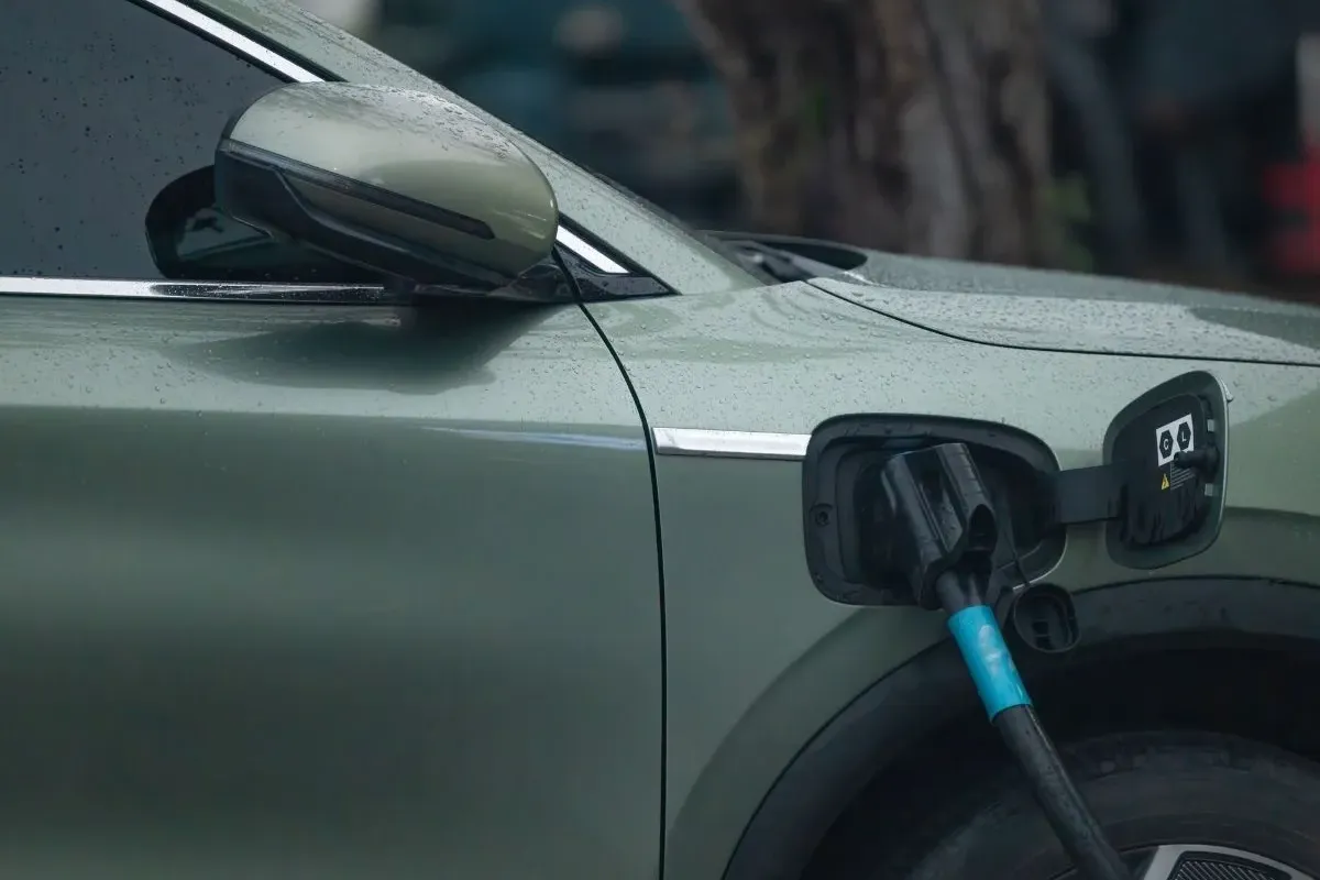 Vehículo eléctrico recorriendo una carretera de montaña con la ciudad al fondo